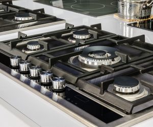 Gas stove with stainless tray selling in appliance retail store, closeup