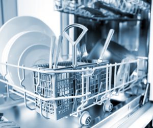 Open dishwasher with clean glass and dishes selective focus